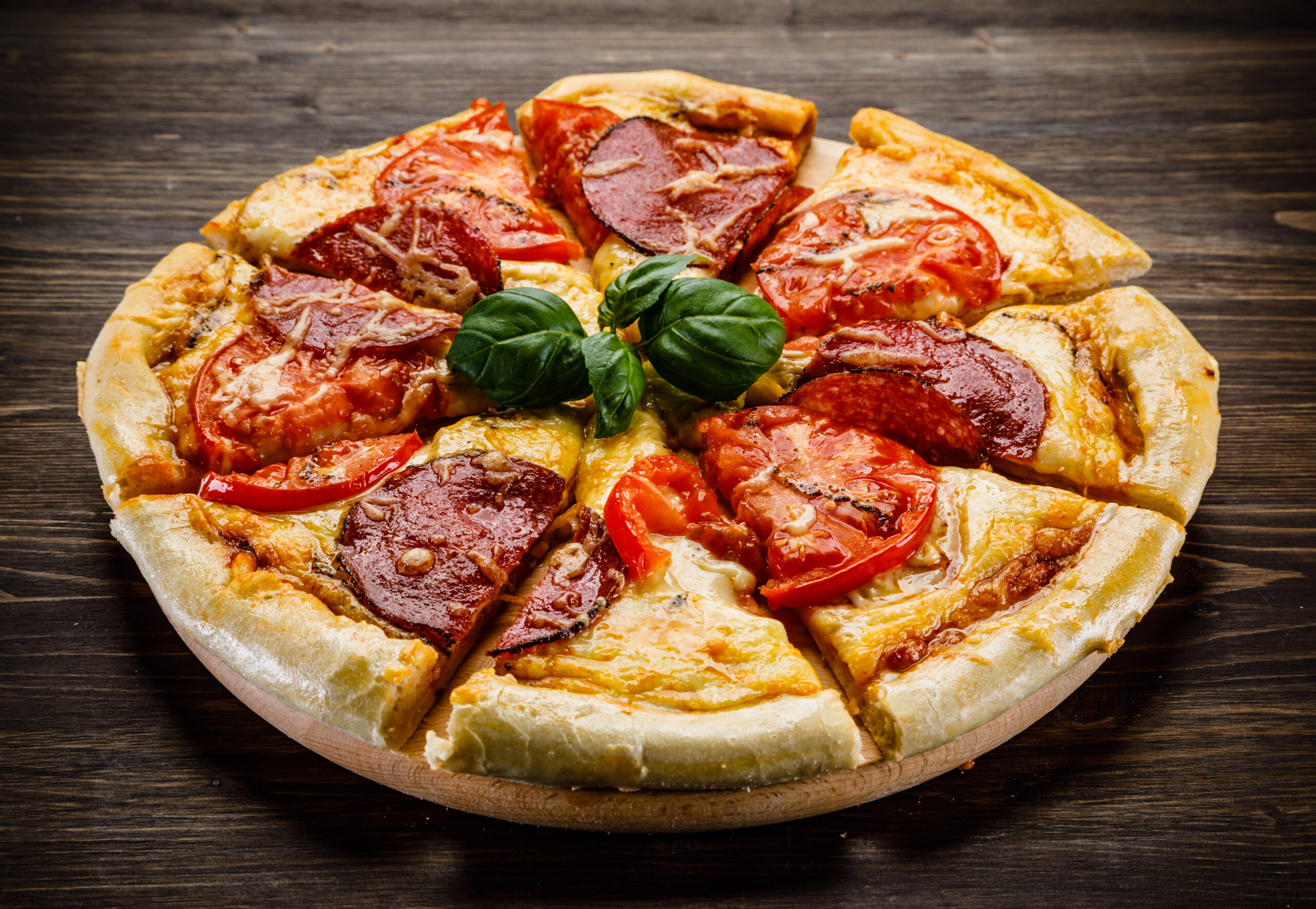 Pizza margherita with ham and pepper on wooden background